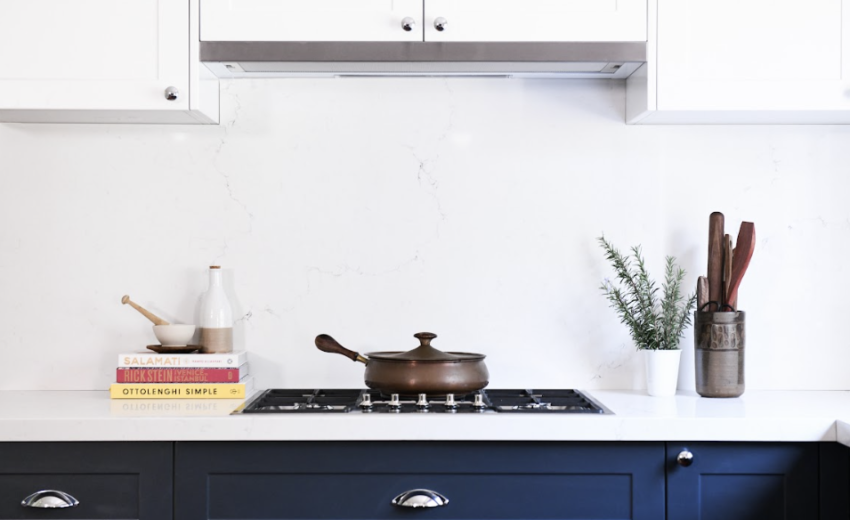 Contemporary kitchen with navy blue cabinets, a sleek quartz backsplash, and a matching quartz range top, creating a cohesive and sophisticated design.
