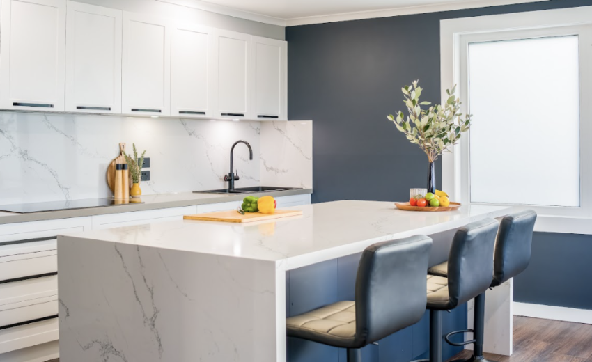 Modern kitchen featuring white shaker cabinets, a navy blue accent wall, and sleek quartz countertops for a clean and elegant design.